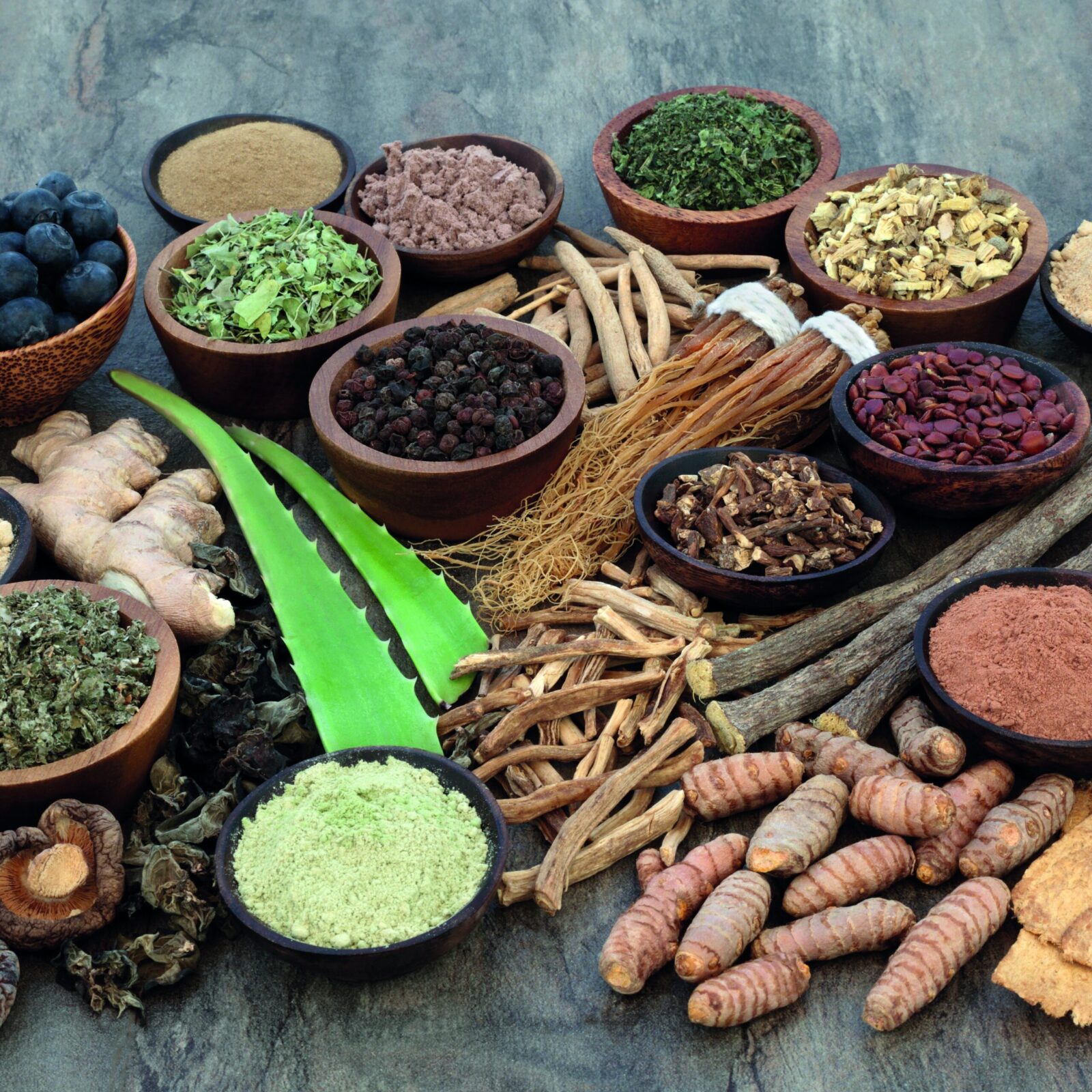 Un mélange visuel de différentes plantes adaptogènes, y compris des racines d'ashwagandha, des tranches de ginseng, de maca etc...