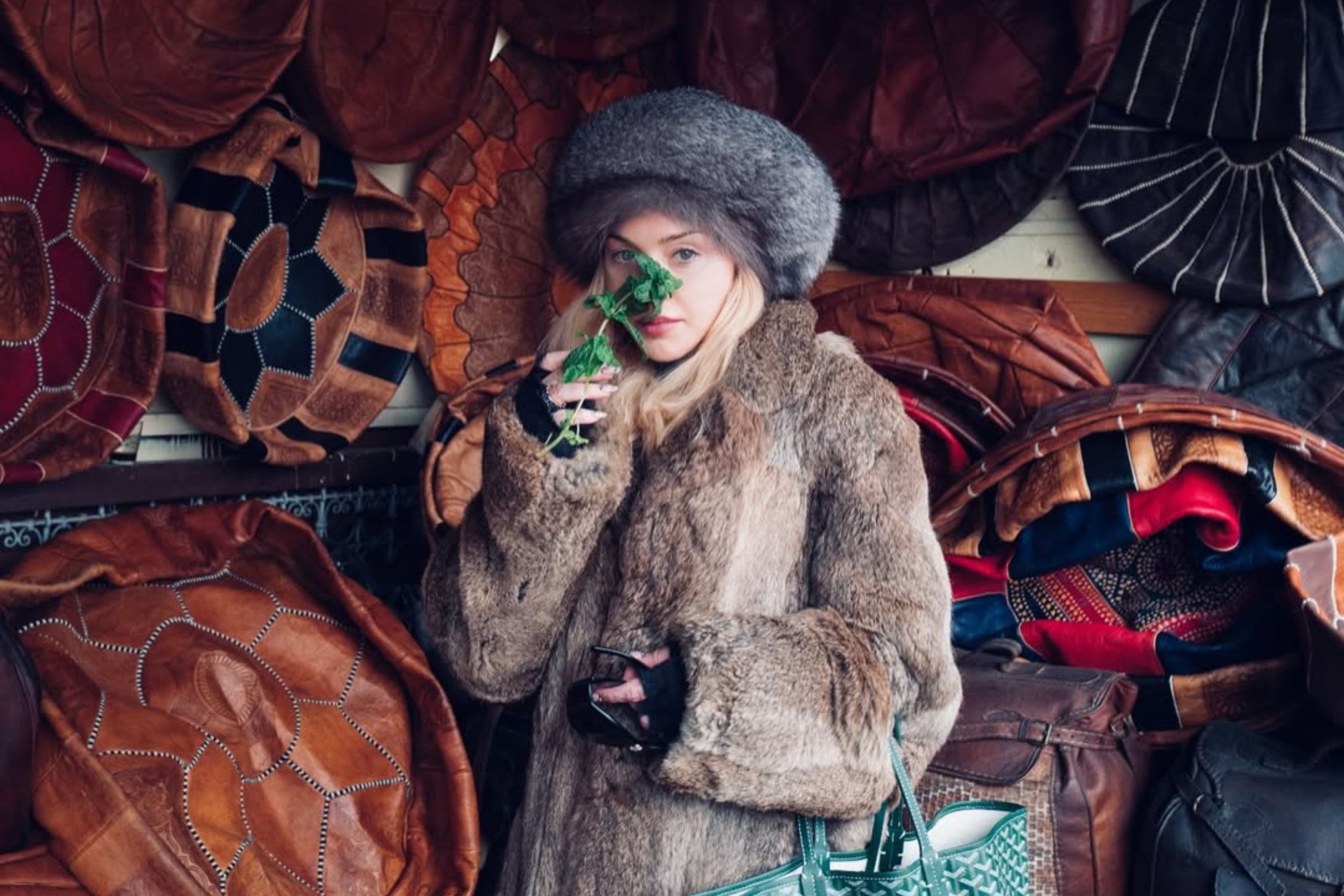 Madonna à Marrakech portant une fourrure et un béret russe, respirant une feuille de menthe, entourée de poufs d’artisanat marocain lors de son séjour “Moroccan Holiday” au Maroc.